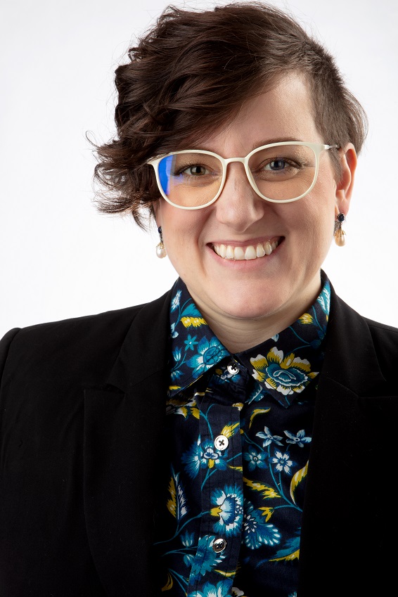 Headshot of Amanda Moore wearing white glasses and a floral button up with a black blazer.